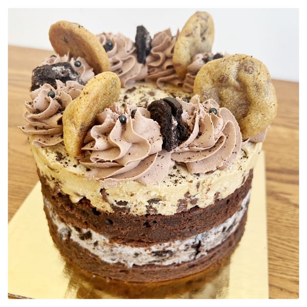 A multi-layered chocolate cake with cookie dough, chocolate frosting, cookies, and Oreo pieces.